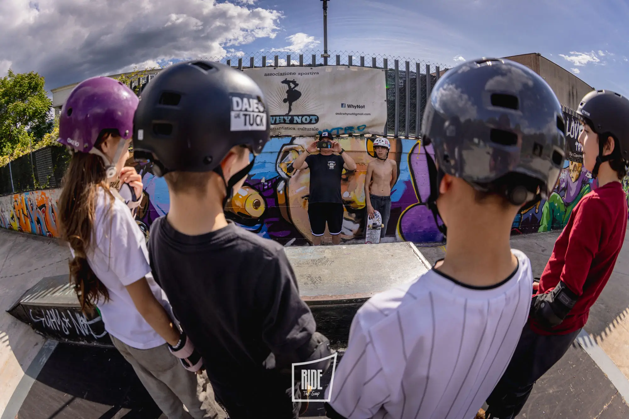 Ragazzi con casco davanti al murale Why Not al WhyNot Skatepark di Colleferro
