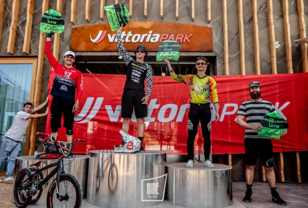 Podio della qualifica UCI Pump Track al Vittoria Park, con i tre atleti che festeggiano davanti al banner dell'evento